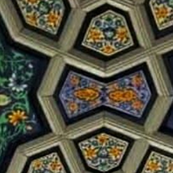 Two badamdar almond forms painted in orange, facing each other across a blue khatamband ceiling panel.