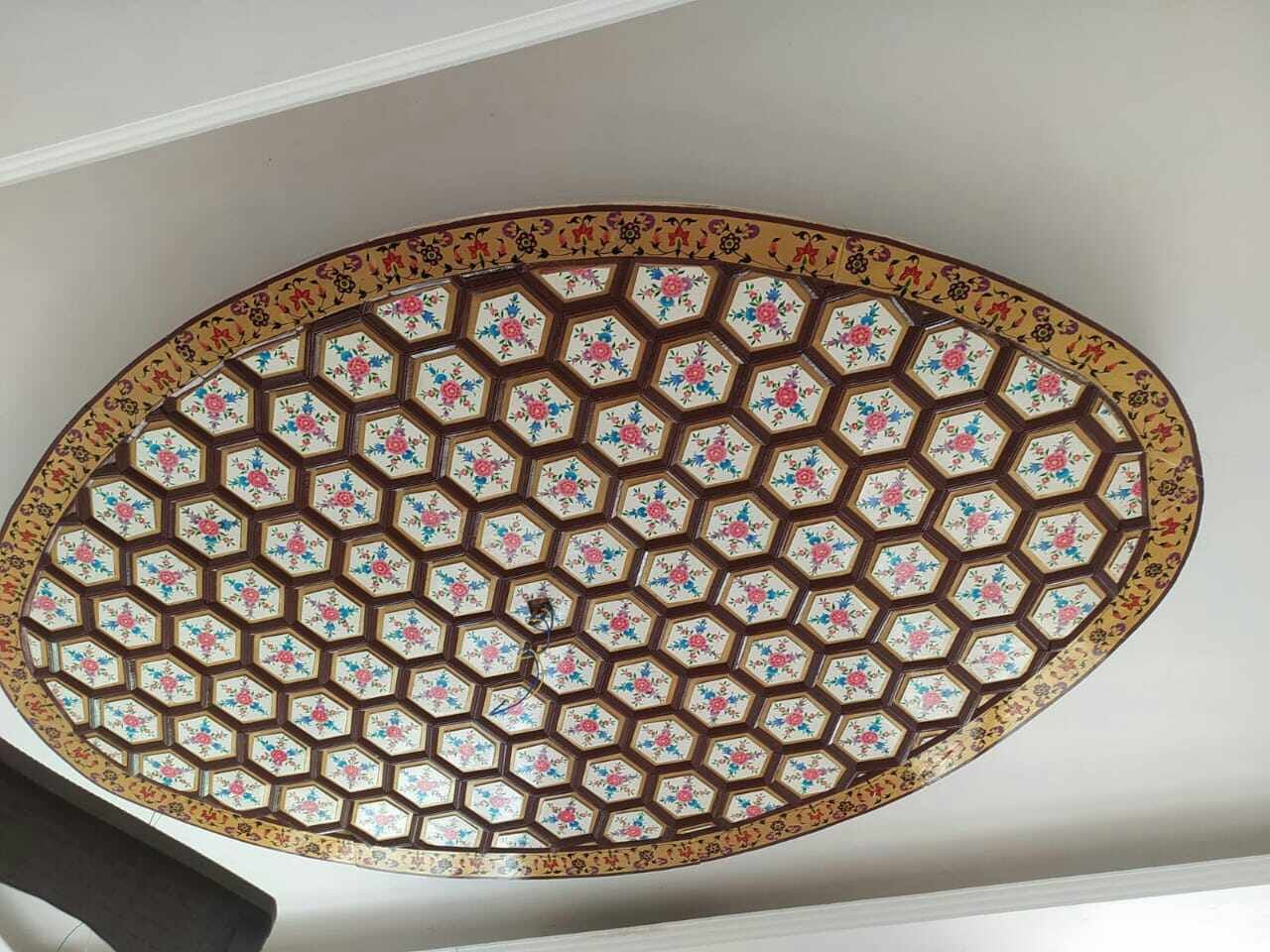Oval khatamband ceiling of ivory hexagons each painted with a small rose spray, edged with a gold floral border band.
